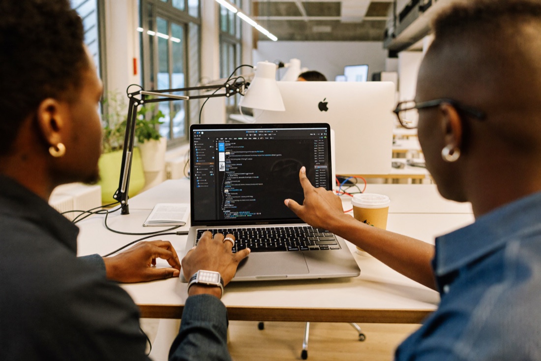 Two people working through code together at a laptop
